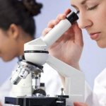 Laboratory assistants looking through a microscope